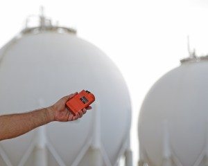 Worker Using a Leak Detector near Gas storage tanks and Lines